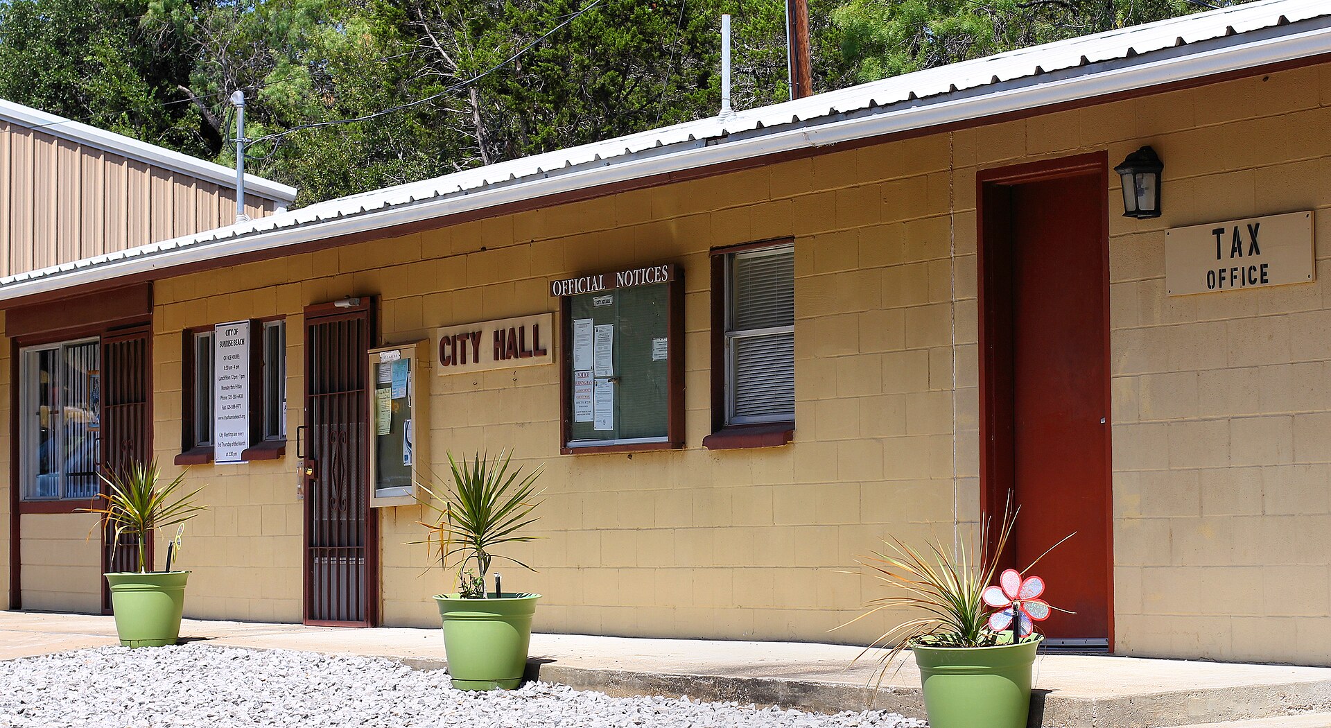 Tan cinderblock building with "City Hall" and "Tax Office" signs