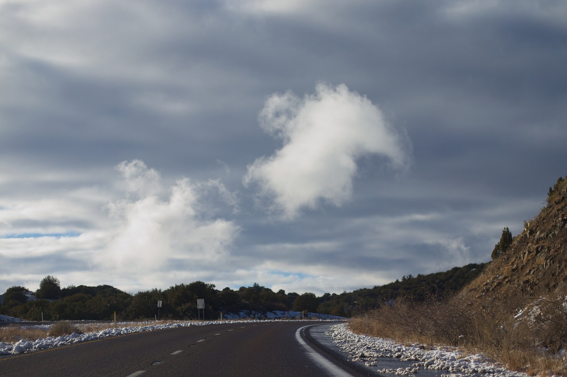 A highway descending toward Payson, Arizona, beneath dark, dramatic storm clouds.