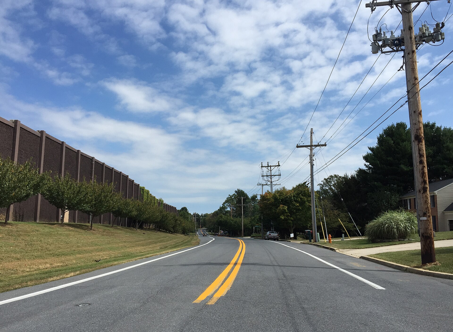 A two-lane suburban road lined with trees and utility poles in Scaggsville, Maryland.