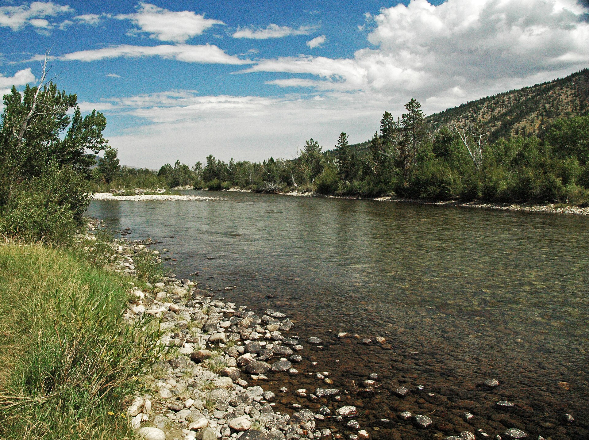 Rocky riverbank along the Stillwater River near Nye, Montana, with forested hills