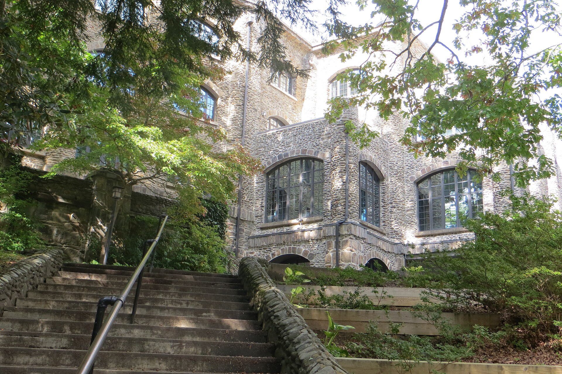 A stone building with exterior stairs and arched windows, the Assembly Inn in Montreat, surrounded by trees.