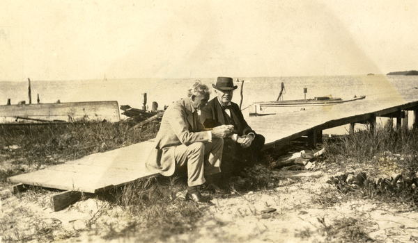A vintage photograph of Henry Ford and Thomas Edison seated on a wooden dock at Punta Rassa, Florida.