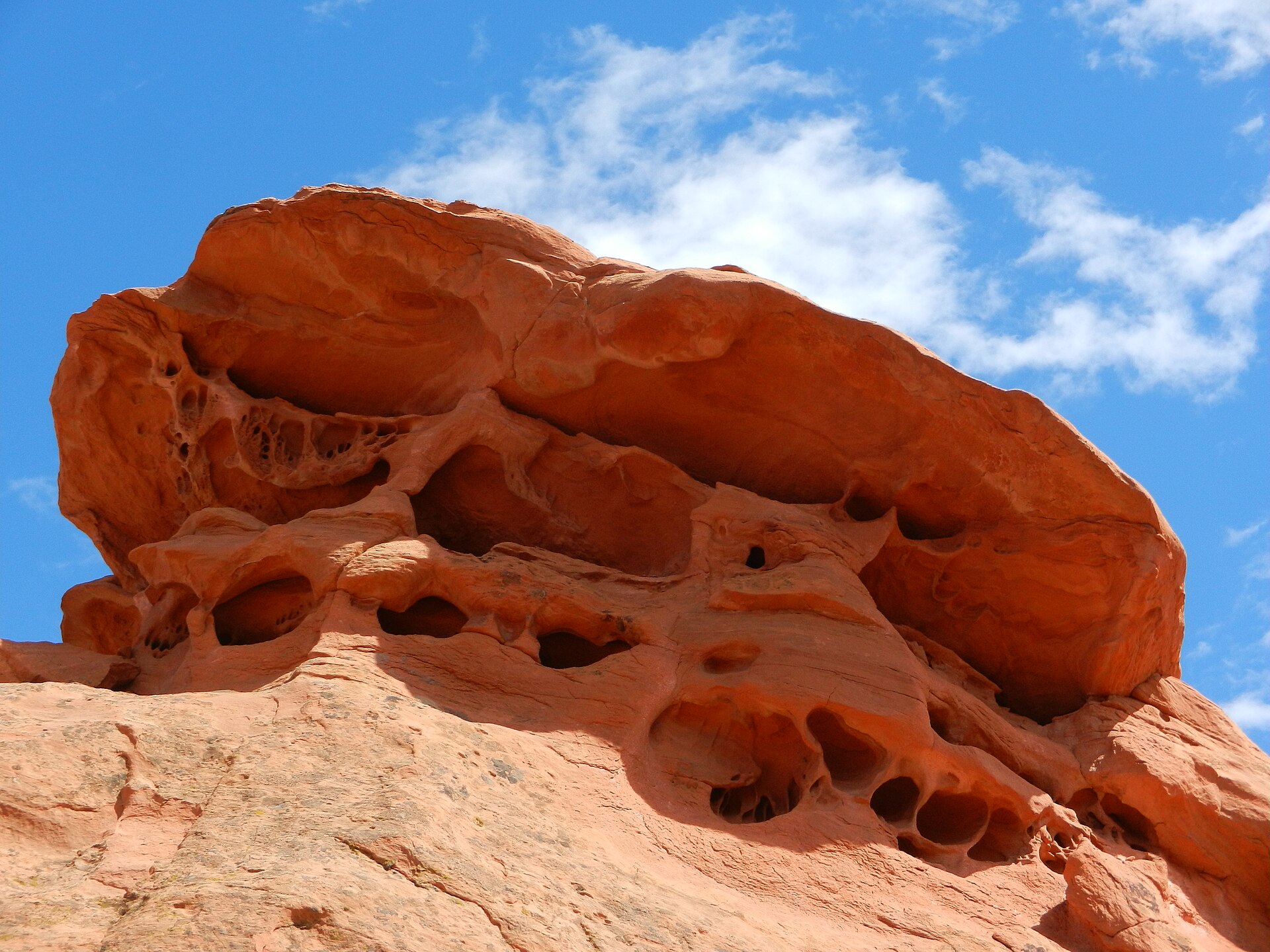 A red-orange sandstone rock formation known as Lion's Head under a blue sky near Teasdale, Utah.