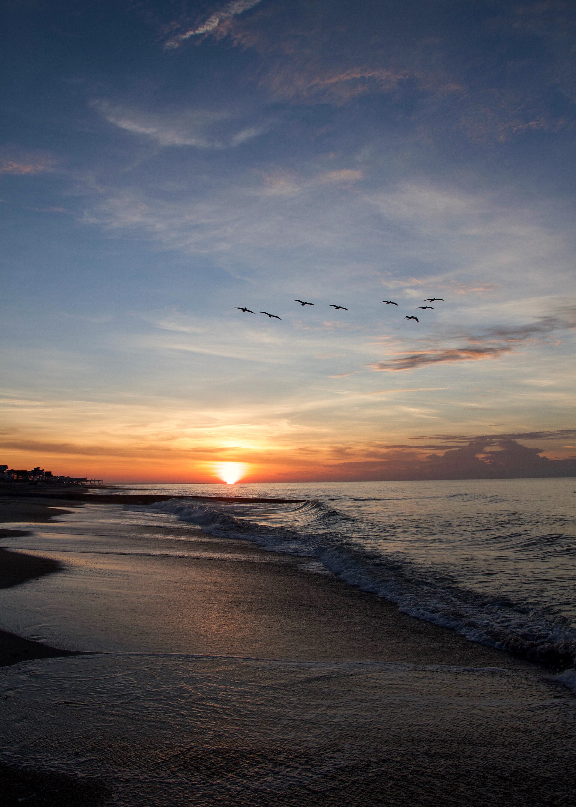 A sunset over the ocean at Edisto Beach, South Carolina, with waves and wet sand.