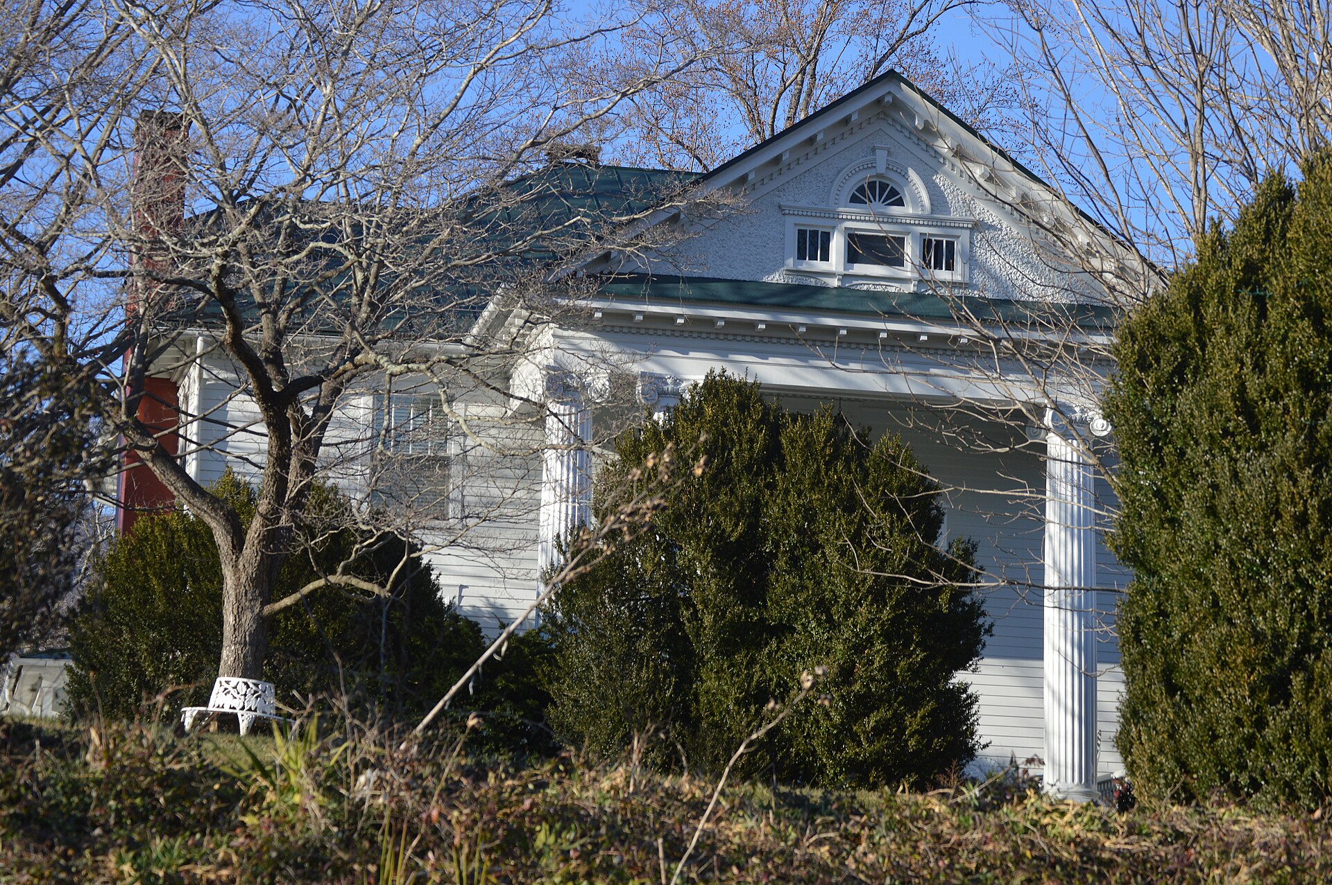 White columned 1810 Elk Hill farmhouse framed by bare trees