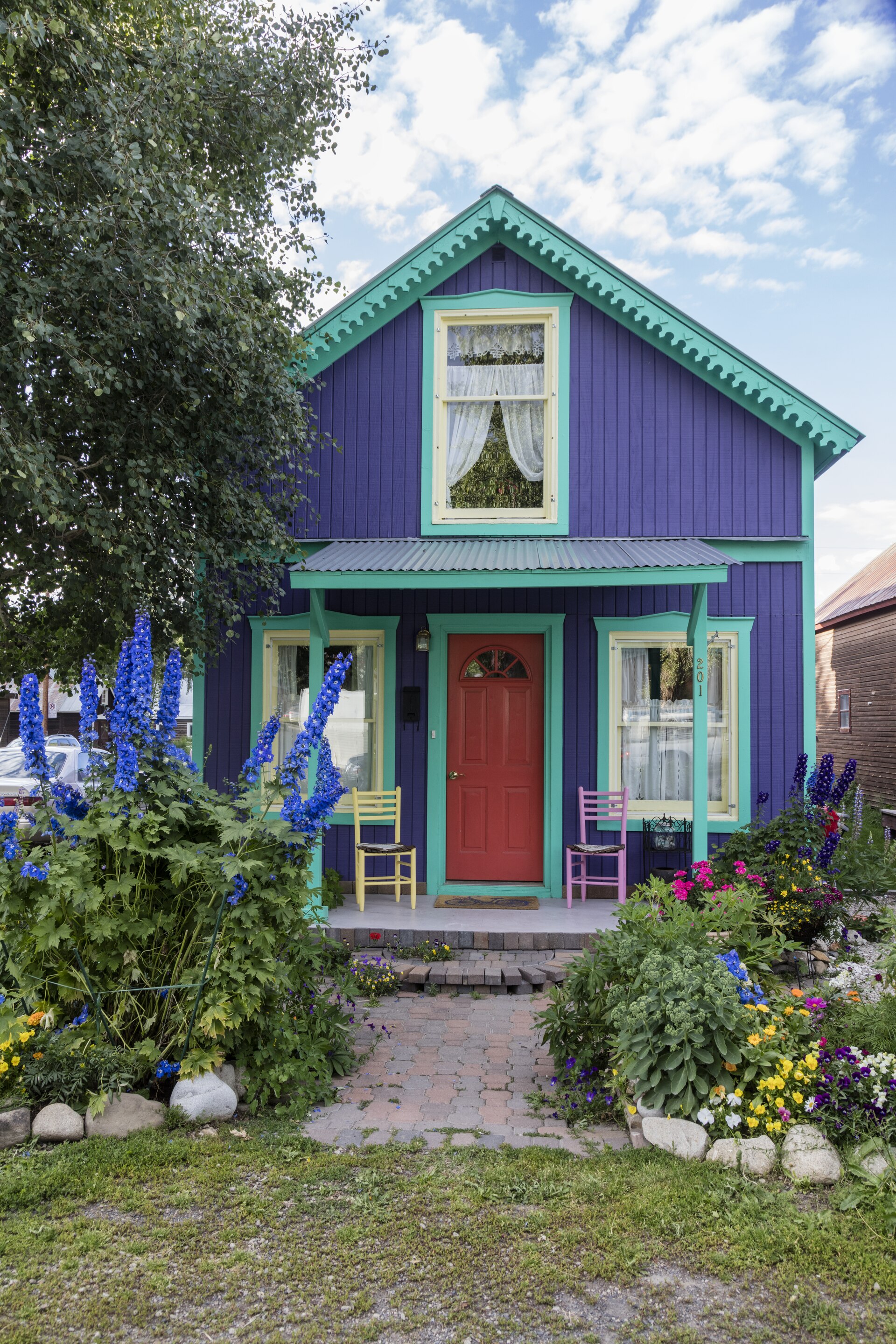 Title: A colorful cottage that matches the purple lupin flowers out front in Crested Butte, a town heavily populated during ski season located high in the Rocky Mountains in Gunnison County,...