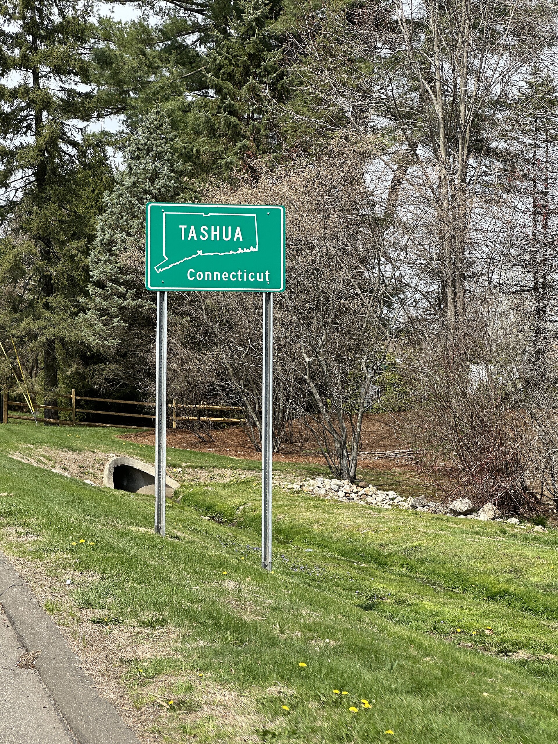 A green highway sign reading Tashua beside a road in Connecticut.
