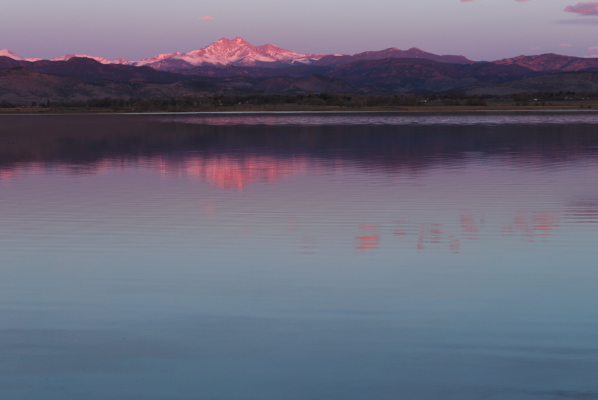 Snow-capped Mount Meeker glowing pink at sunrise, reflected in McIntosh Lake