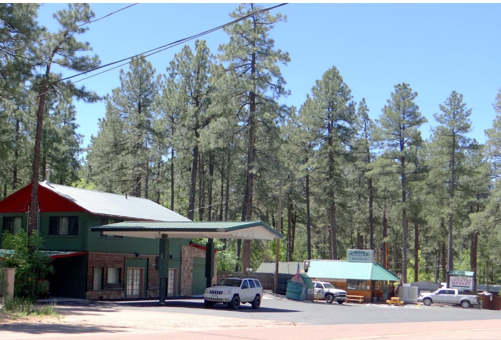 A small general store with gas pumps surrounded by tall ponderosa pines in Christopher Creek, Arizona.