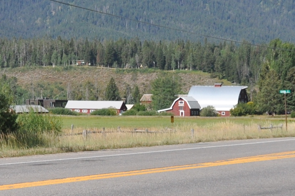 Historic wooden barns with snow-dusted roofs set against the Teton foothills.