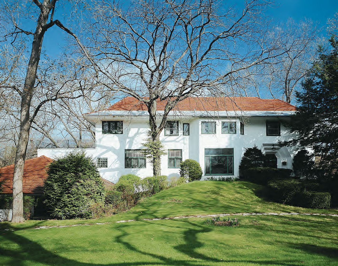 The white facade of a large house with a clay tile roof in Long Beach, Indiana.