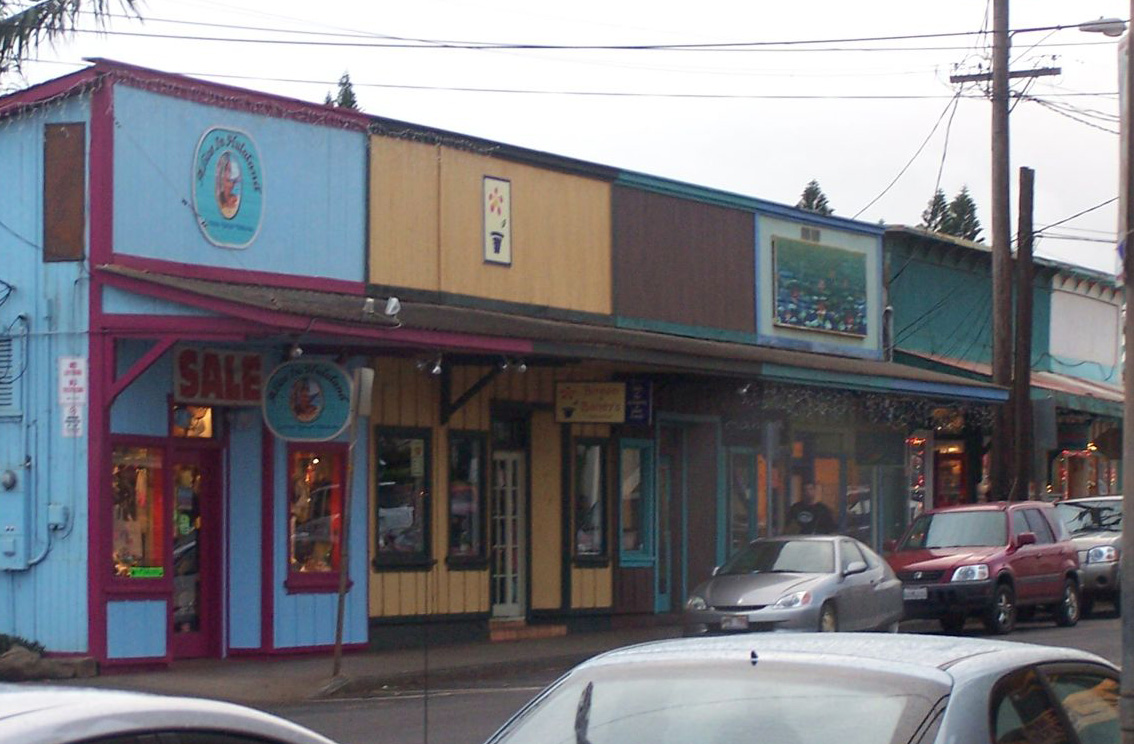 Brightly painted shop fronts in pink, blue, and yellow with a 'SALE' sign and parked cars.