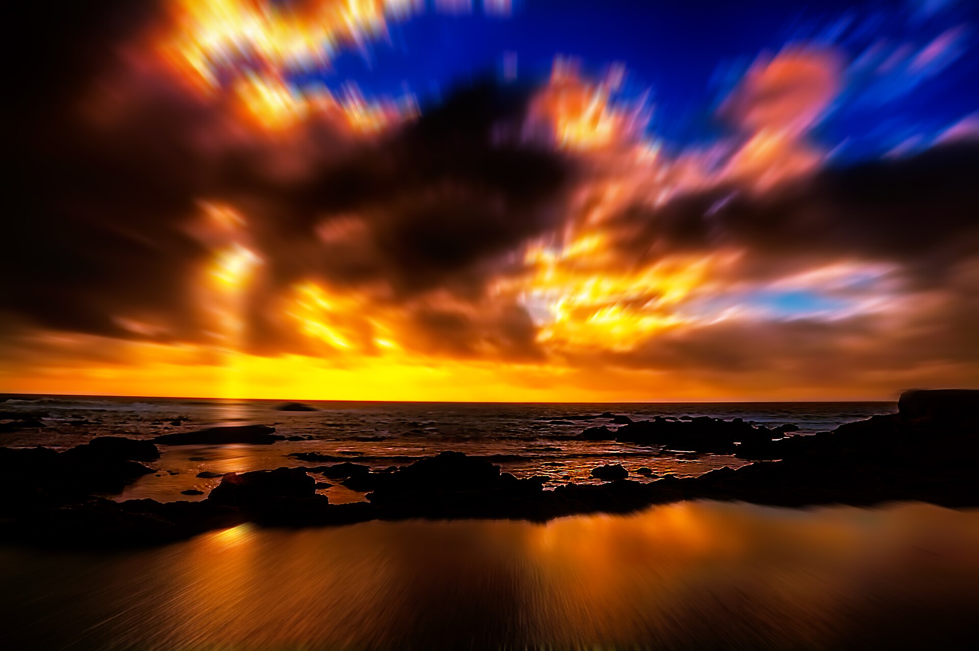 Sunset over waves breaking on a rocky tide pool at Glass Beach in Fort Bragg, California
