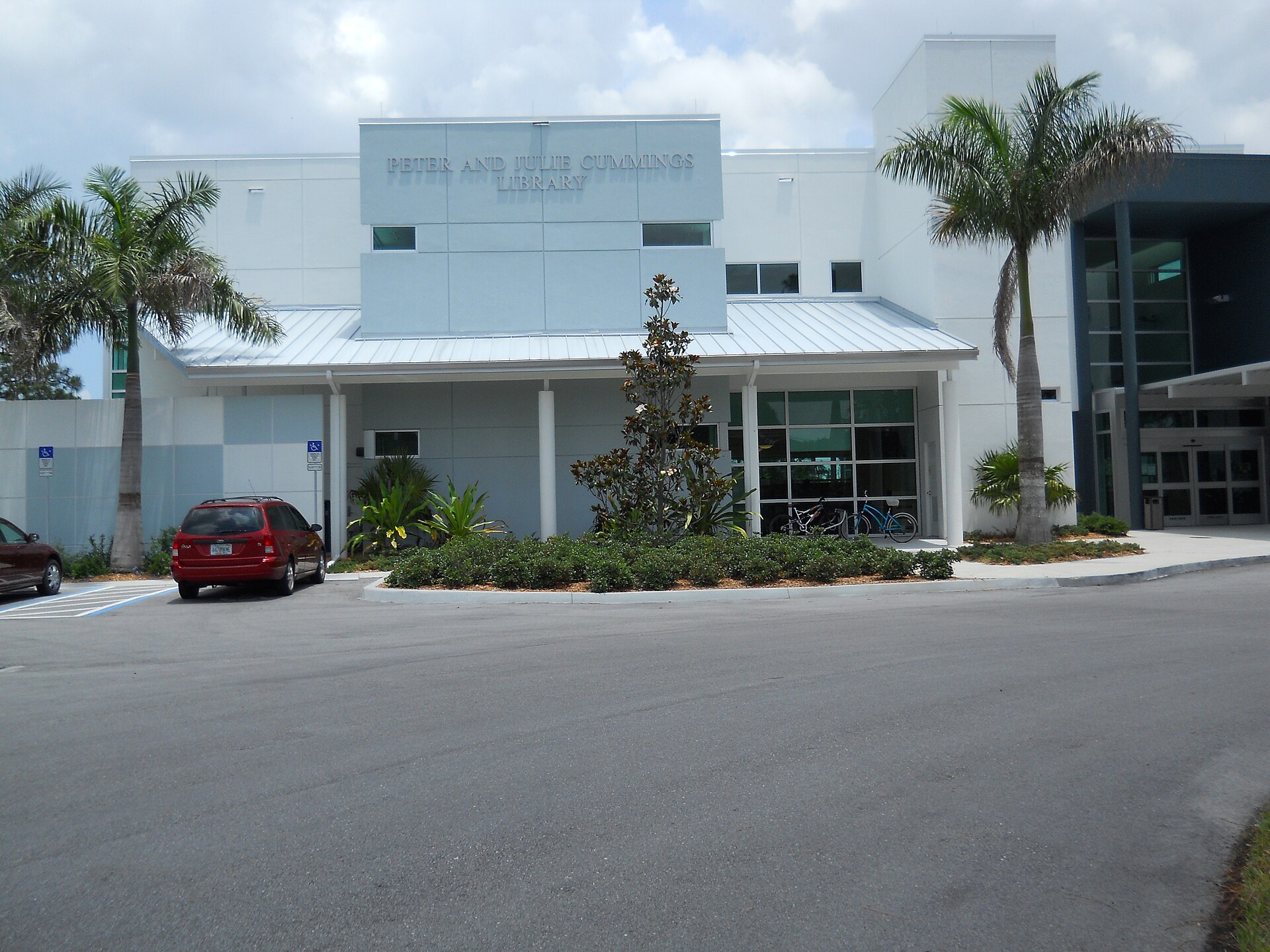 The Peter and Julie Cummings Library building with palm trees