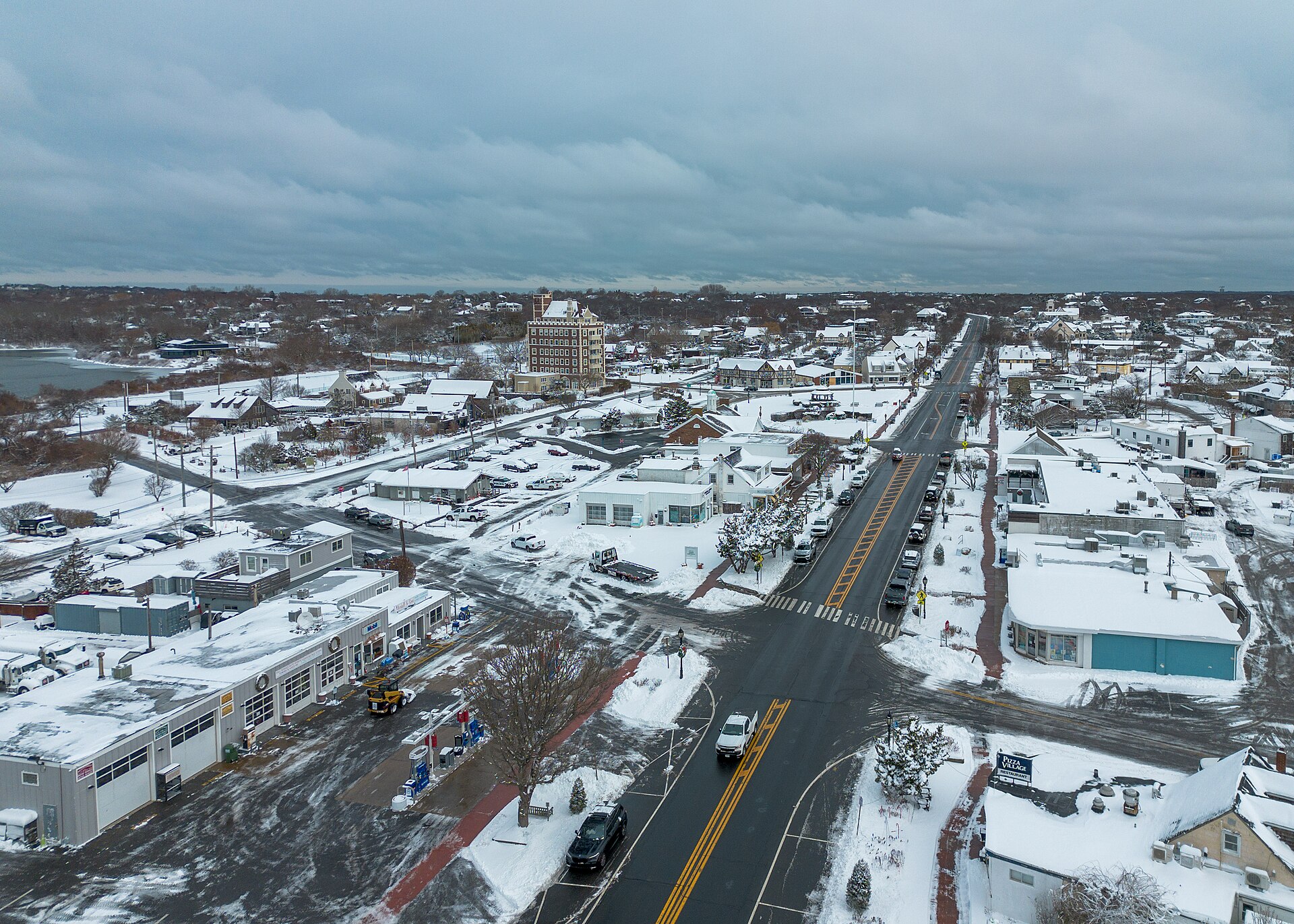 A wide main street with shops and snow-dusted roofs under a gray sky.