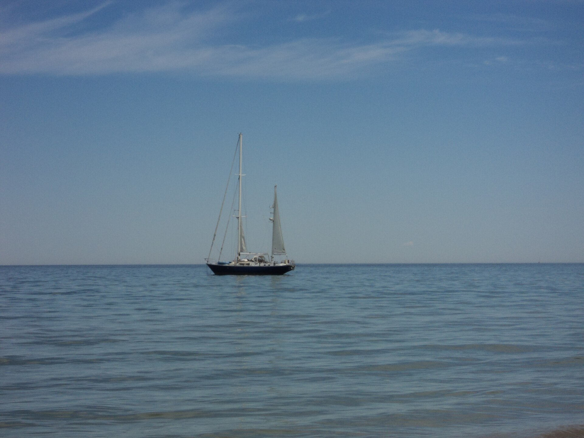 A sailboat anchored in Lake Michigan off Leland Public Beach
