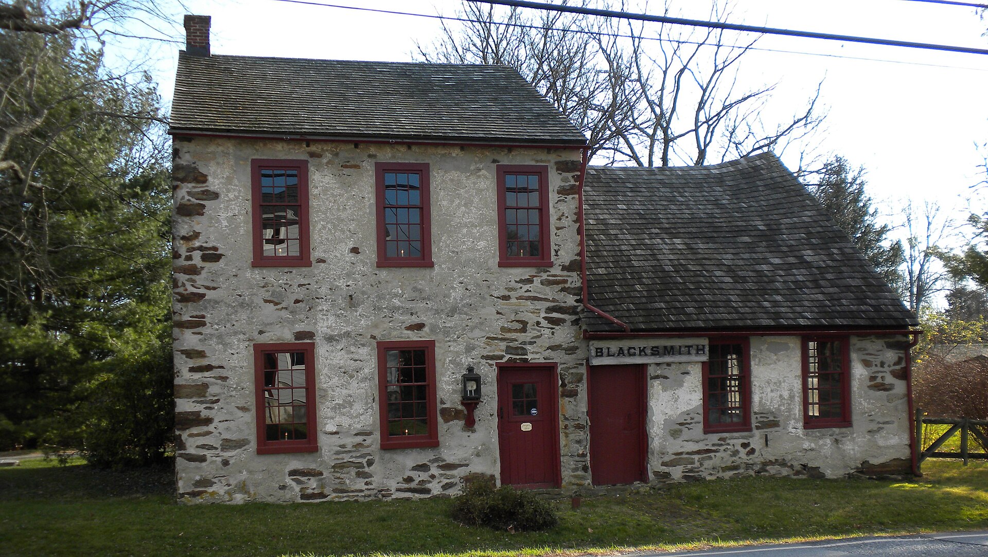 A stone building with a 'Blacksmith' sign and red doors.