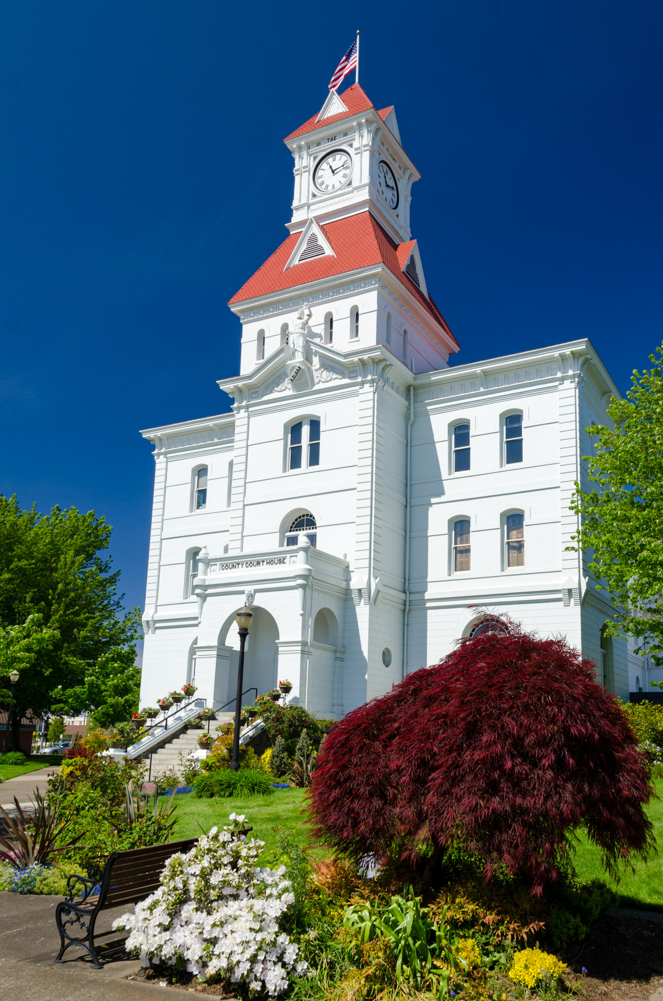 The white Benton County Courthouse with its red clock tower in downtown Corvallis, Oregon