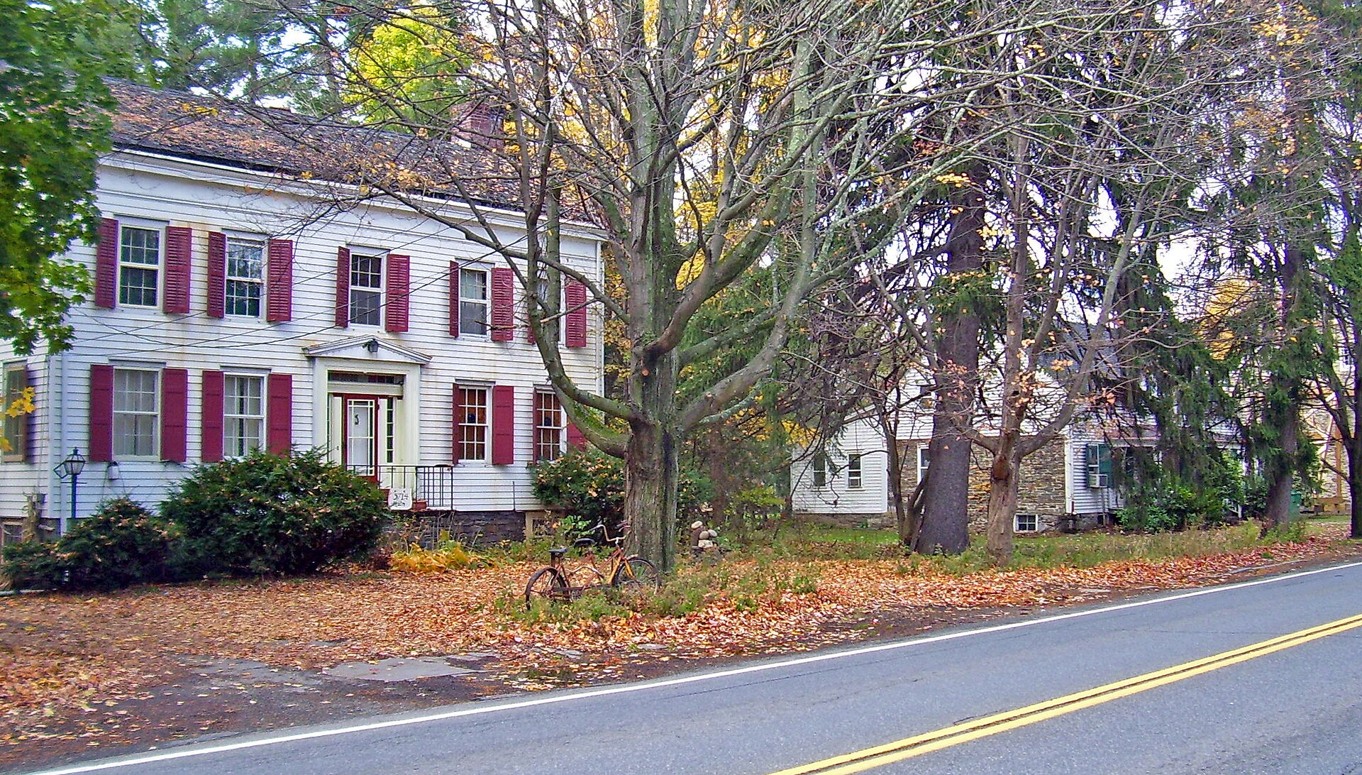 A historic white house with red shutters in Stone Ridge New York.