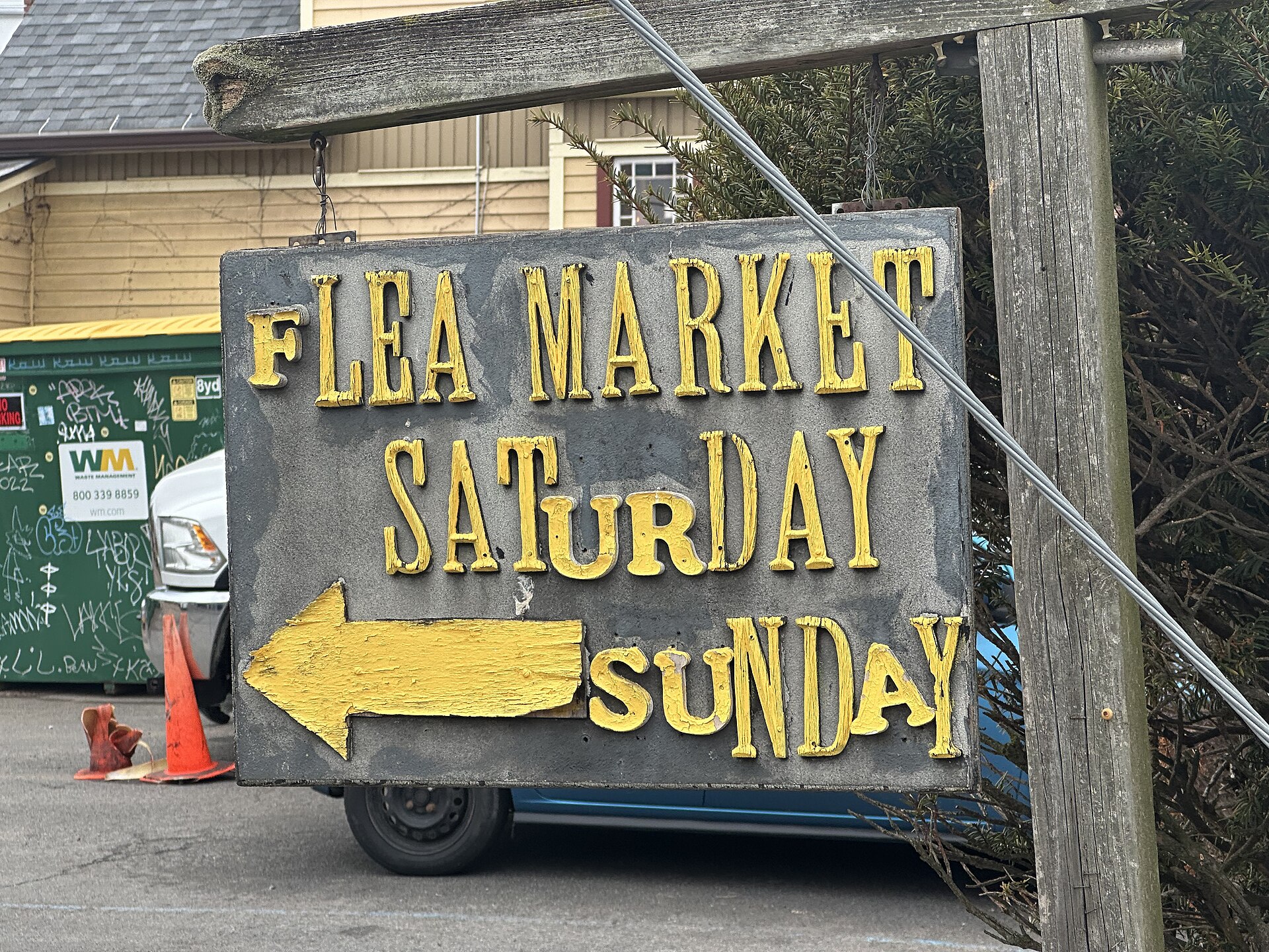 A wooden sign advertising a weekend flea market in Woodstock New York.