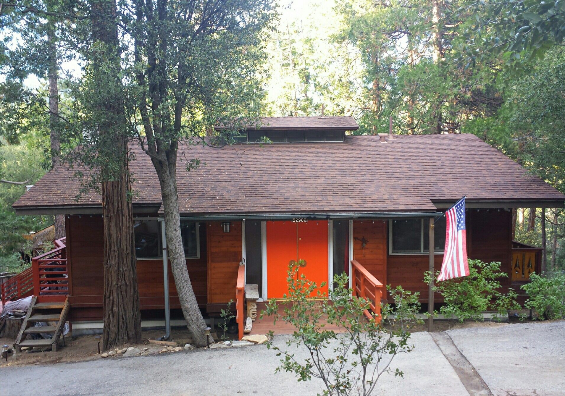 A small wood cabin with an orange door among pine trees in Idyllwild, California, an early Frank Gehry design.