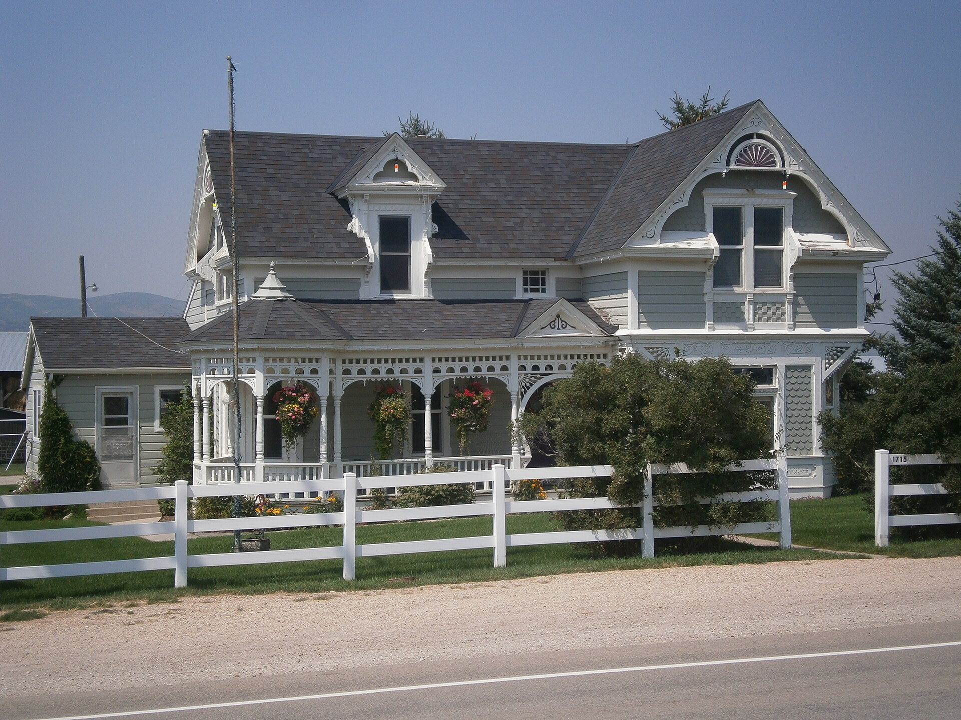 A white Victorian house with a wraparound porch and picket fence in Marion, Utah.