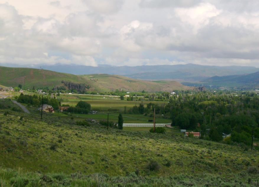 Green rolling valley with fields and hills under a cloudy sky.