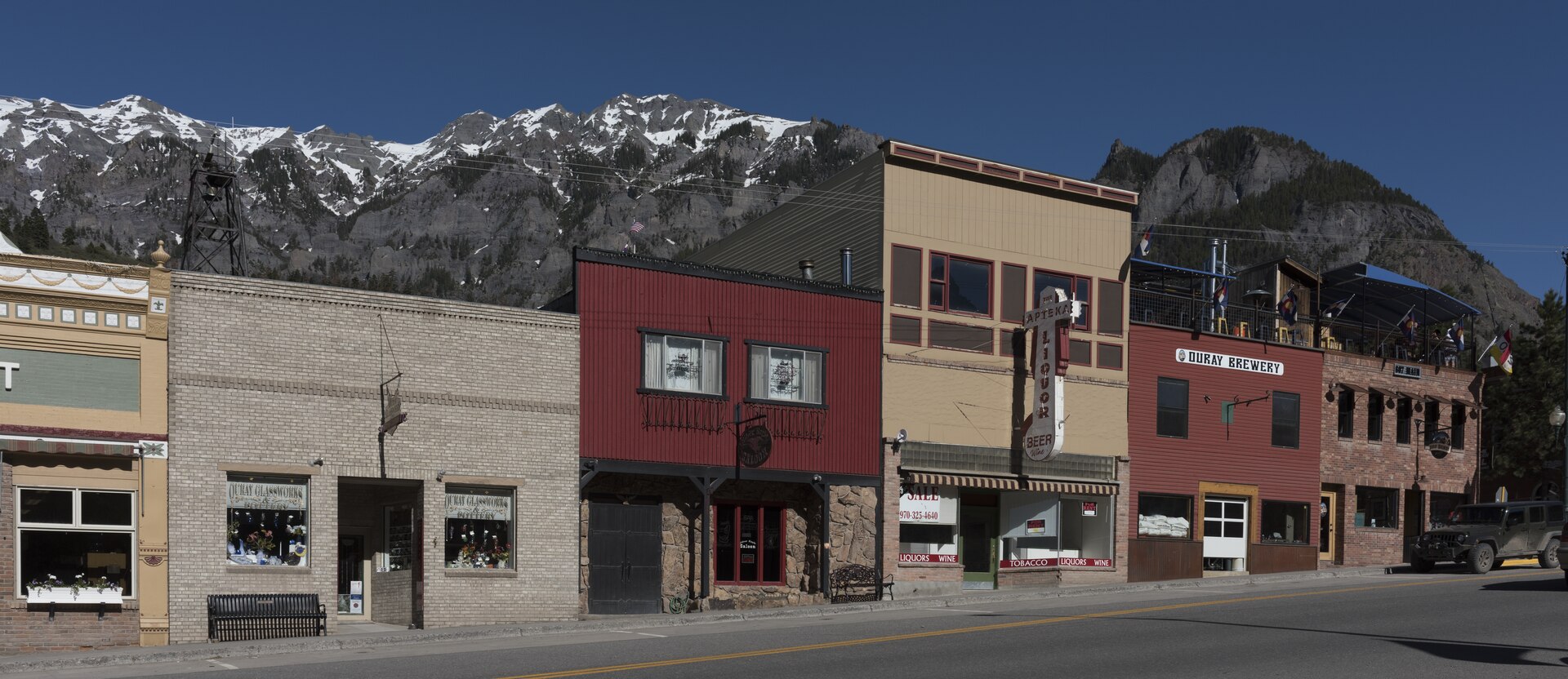Historic storefronts on Main Street in Ouray, Colorado, beneath snow-capped San Juan Mountains