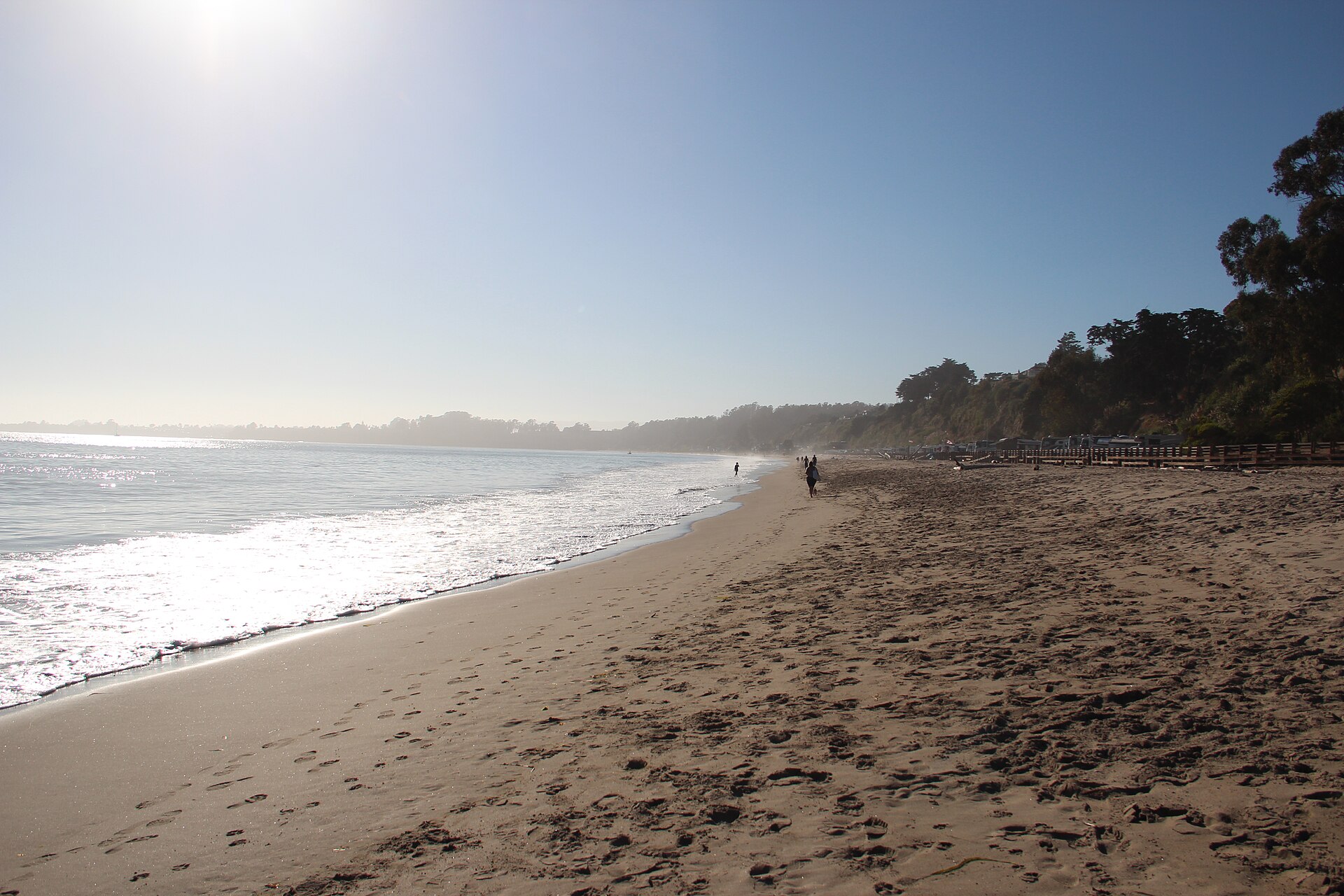 Sunlight on the sand and surf at Seacliff Beach with bluffs in the distance.