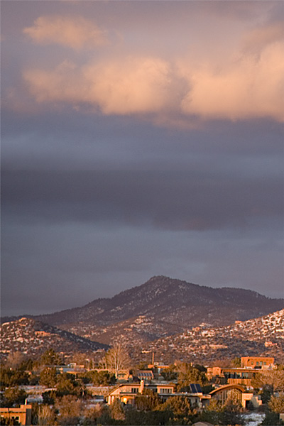 Houses and desert hills of Eldorado at Santa Fe, New Mexico, under a colorful sunset sky.