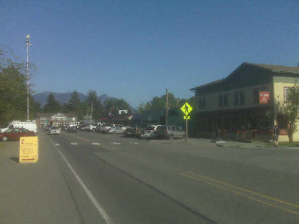 Fall City's main street with storefronts and parked cars on a sunny day.