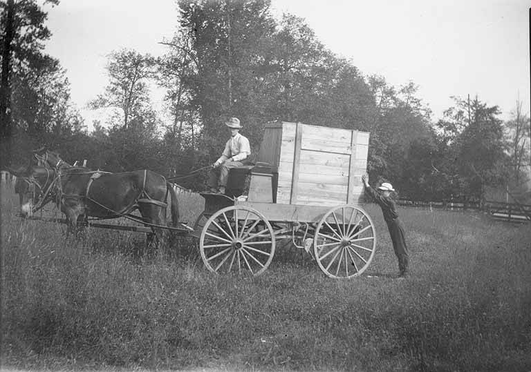 A black-and-white photograph of a man driving a horse-drawn freight wagon in Fall City.