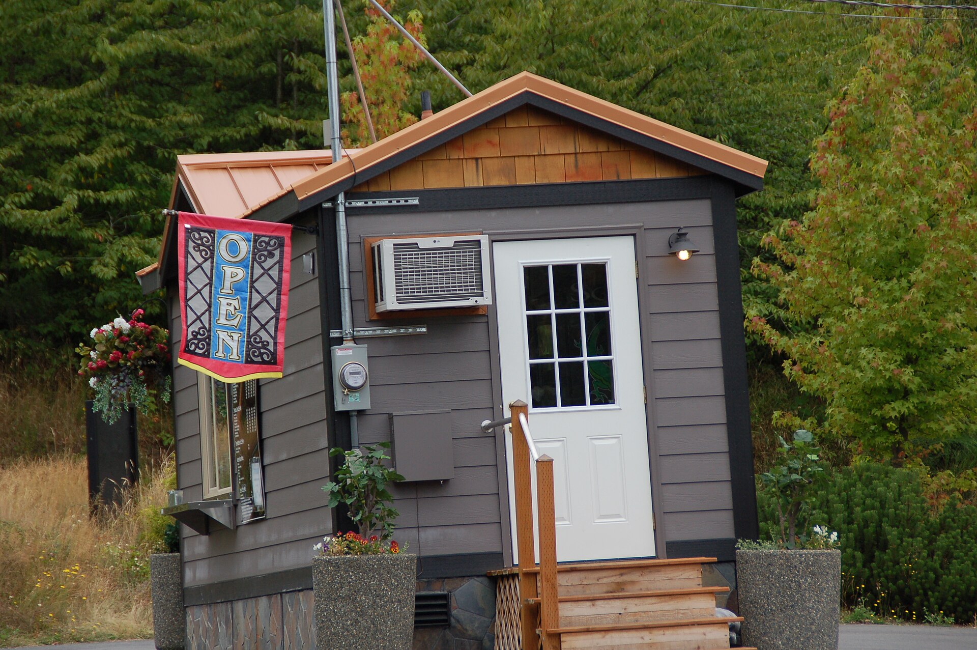 A tiny wooden shop with an 'OPEN' banner on Fox Island, surrounded by evergreens.