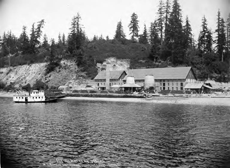 A black-and-white photograph of historic waterfront buildings and a steamer at Fox Island.