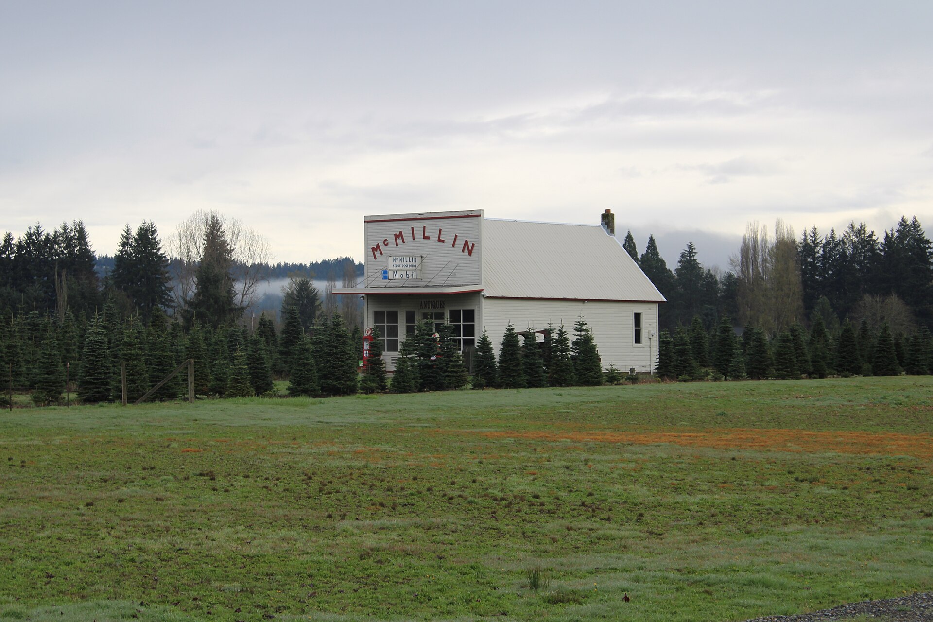 A vintage white gas station building with a McMillin sign in McMillin, Washington.