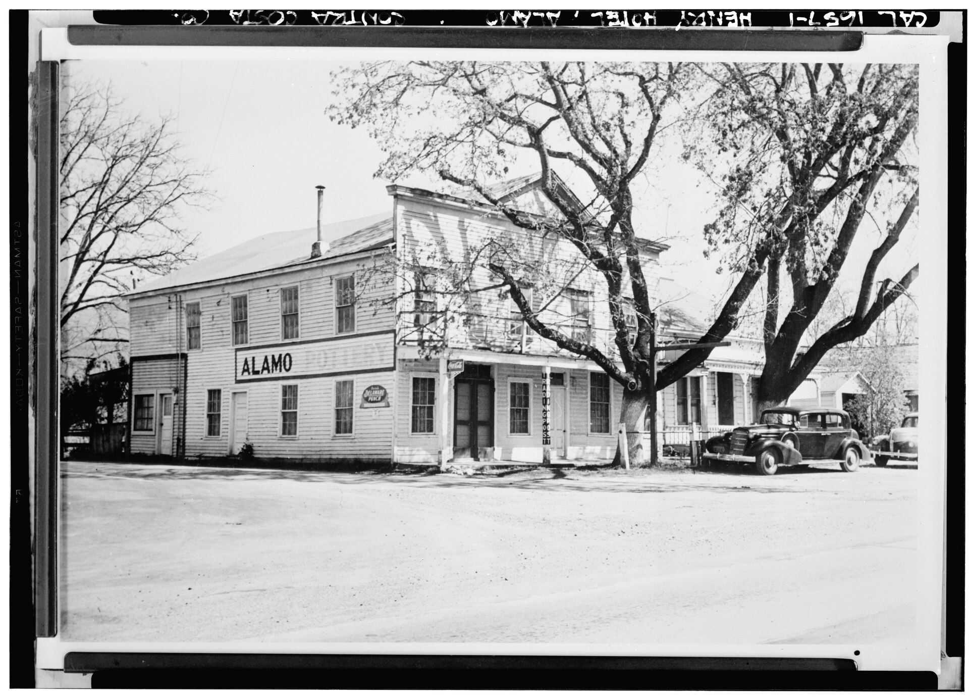 A black-and-white photograph of the historic Alamo store, a two-story wooden building with an 'ALAMO' sign.