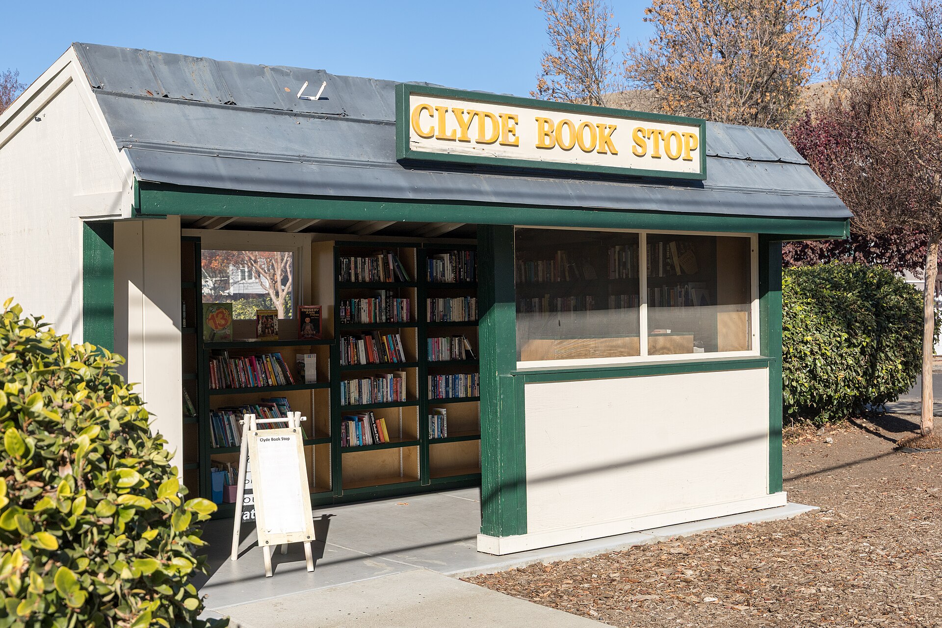A small outdoor book kiosk with a sign reading Clyde Book Stop in Clyde, California.