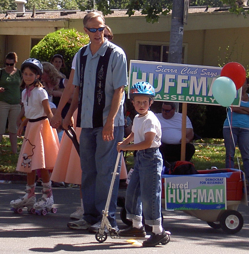 Marchers in the Cotati Kids Day Parade, including a family with campaign signs, in Cotati, California.