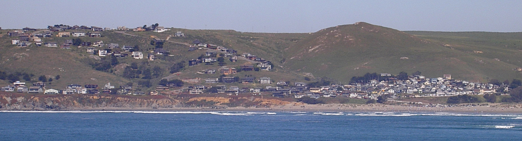 Dillon Beach's houses scattered across the headland seen from the ocean.