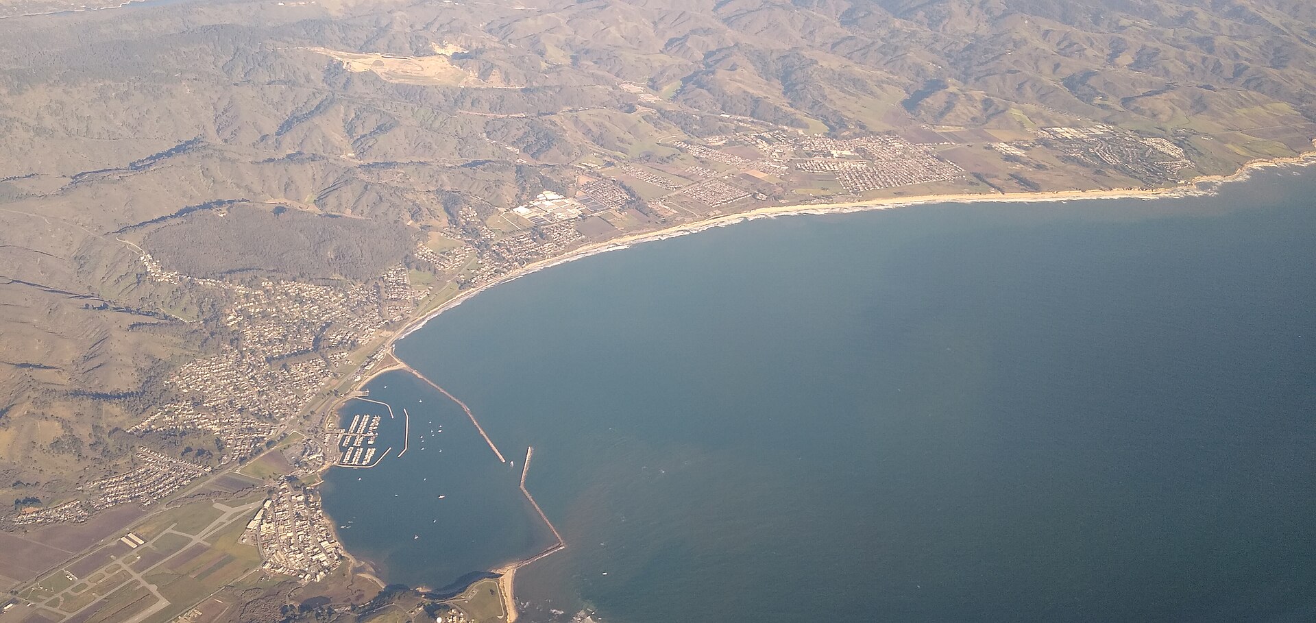 Aerial view of El Granada's coastline with Half Moon Bay Airport's runway visible beside the shore.