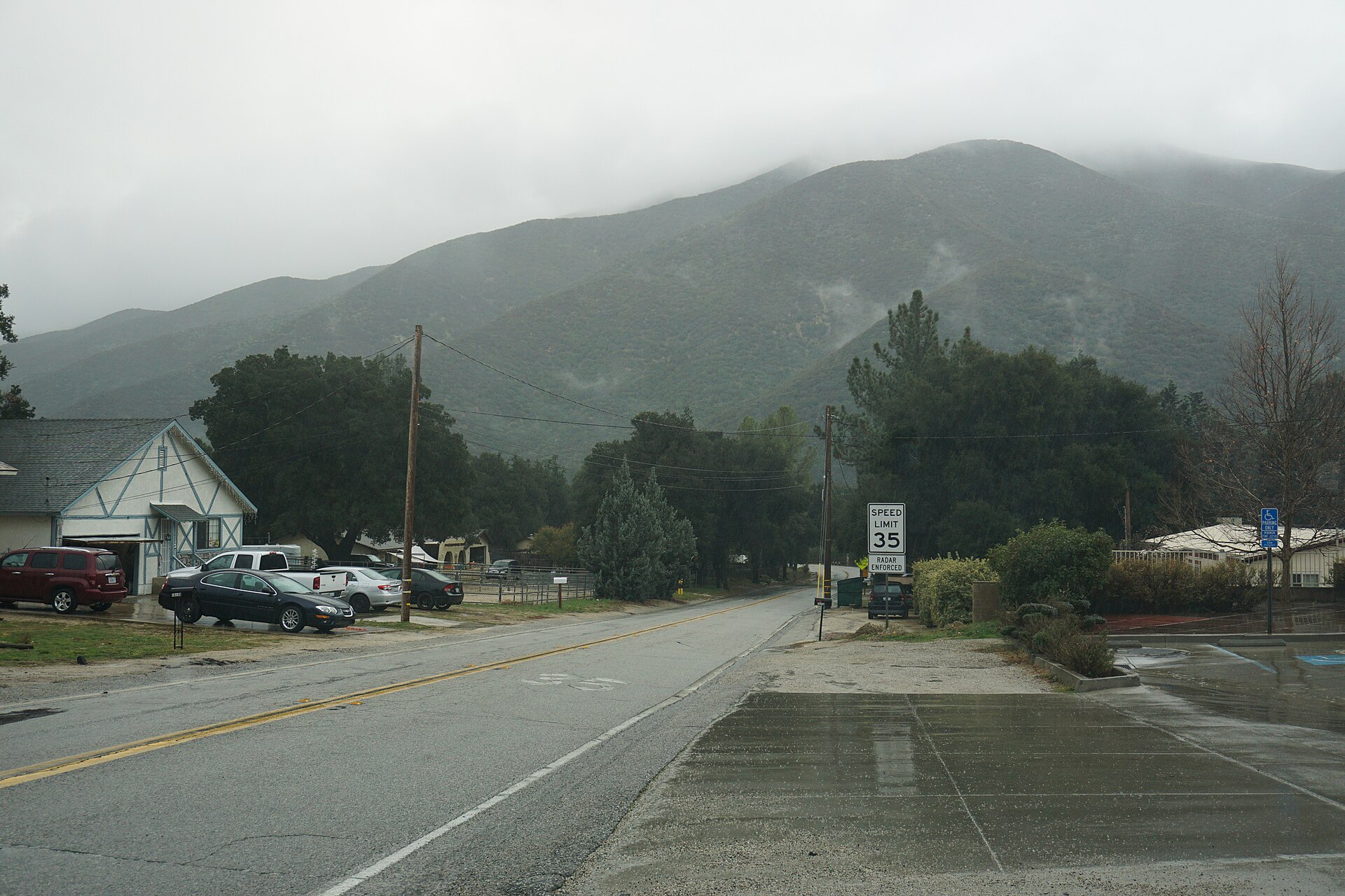 A residential street in Green Valley with homes, parked cars, and a mountain rising behind the town under cloudy skies.