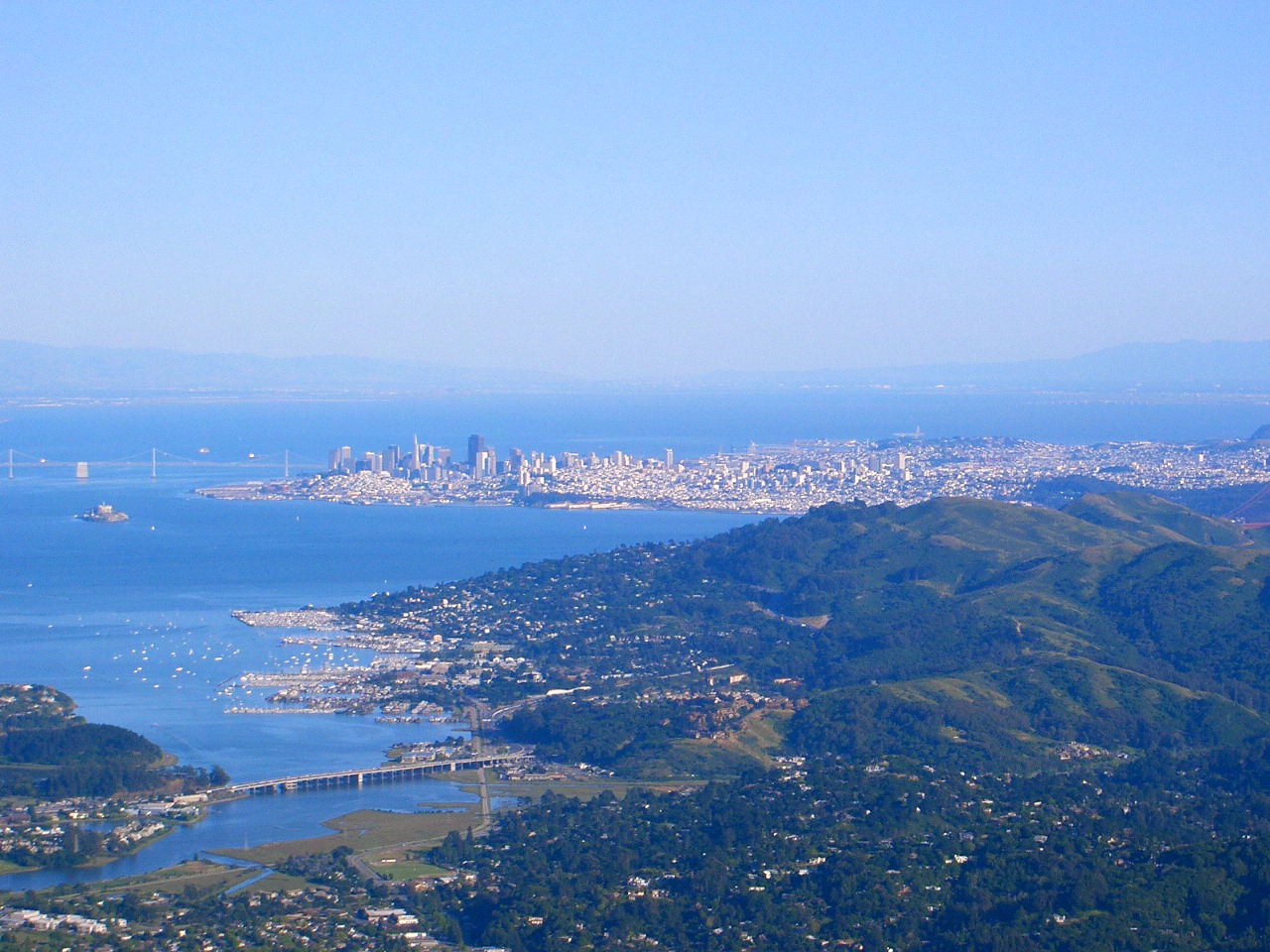 The San Francisco skyline and Bay Bridge seen across the water from the hills above Marin City.