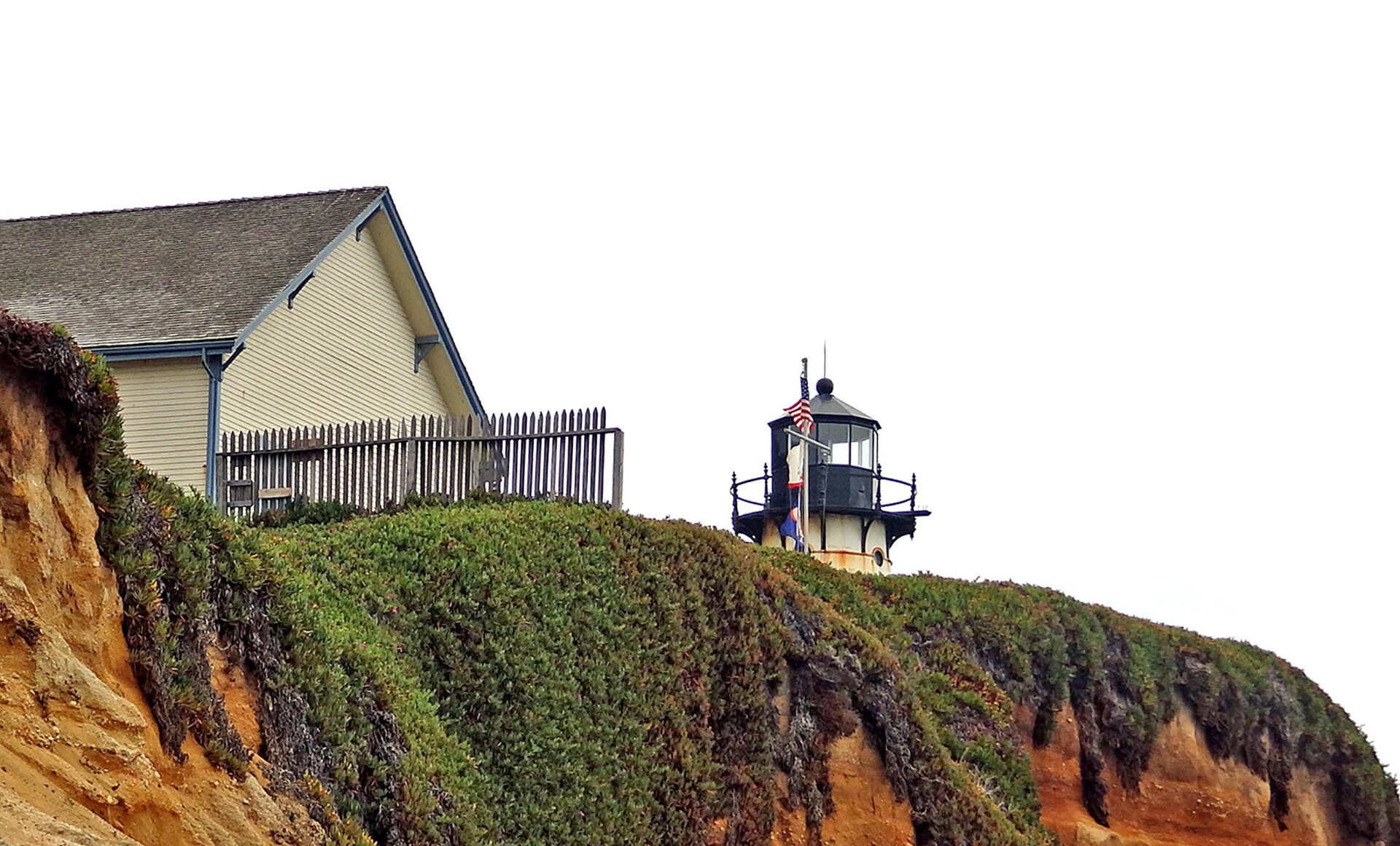 The Point Montara Lighthouse and keeper's quarters perched on an ice-plant-covered cliff above the Pacific.