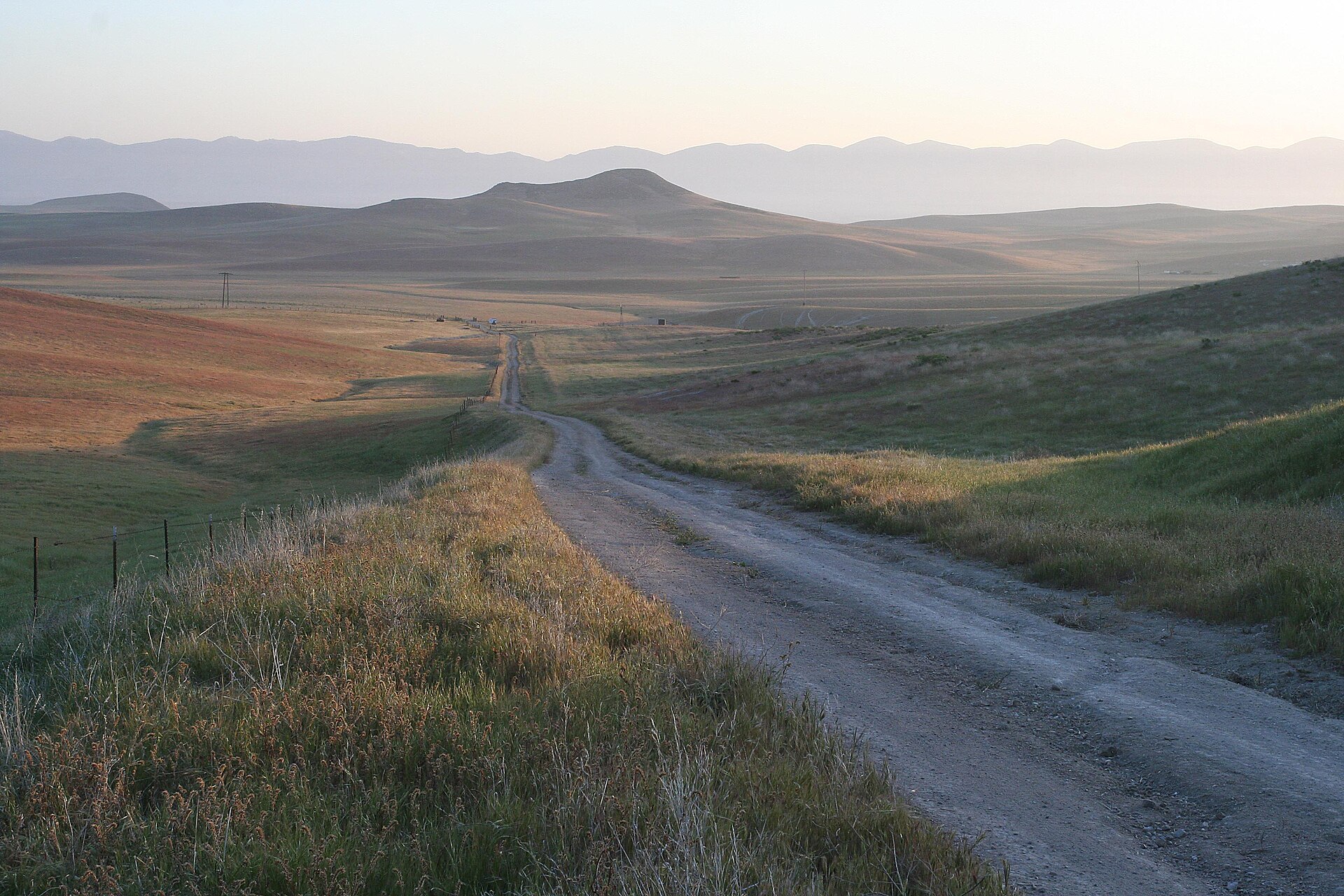 North Gate Road winding through golden rolling rangeland with hills in the distance.