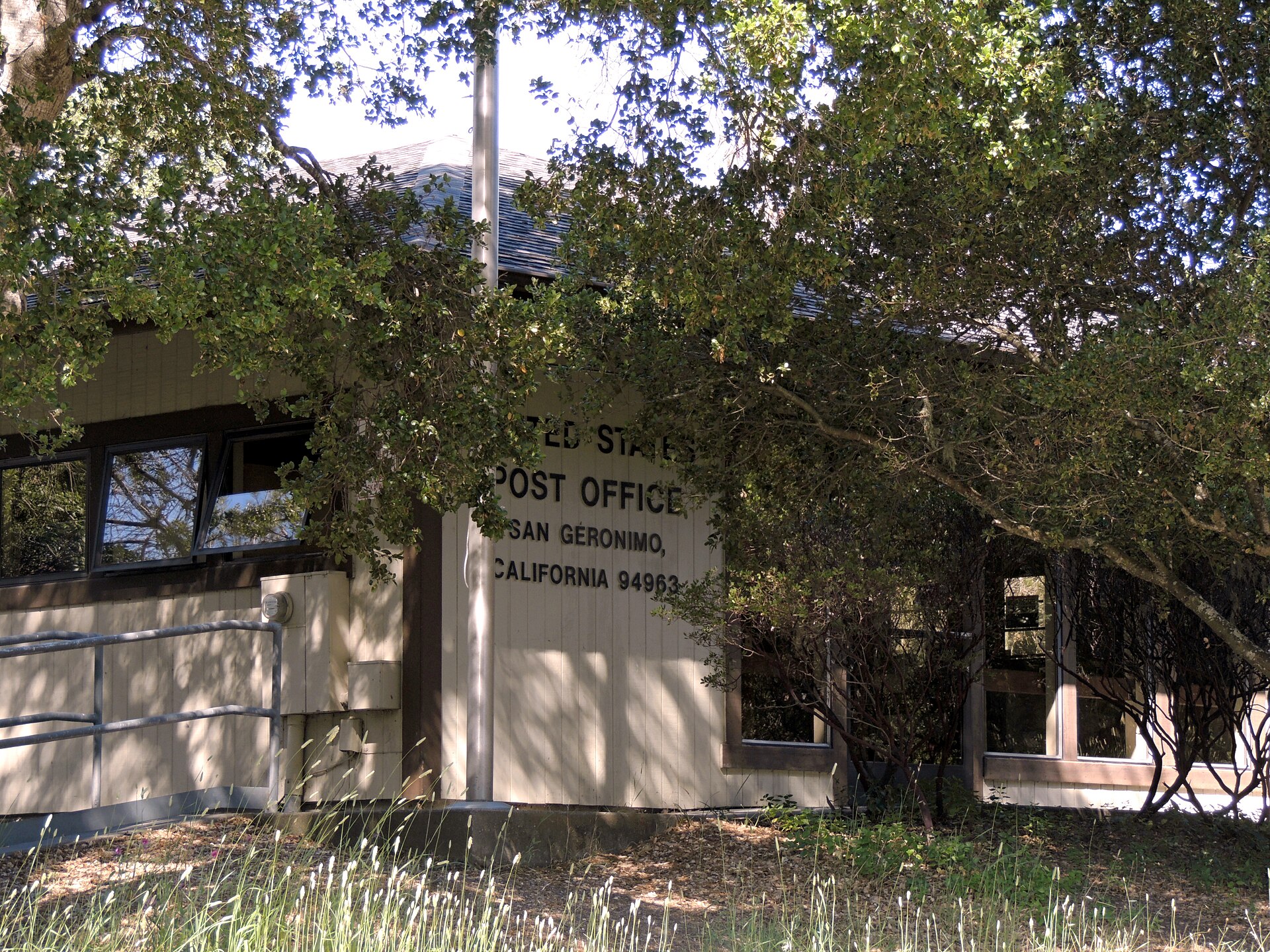 The San Geronimo post office, a small building shaded by oak trees with a 'U.S. Post Office San Geronimo California' sign.