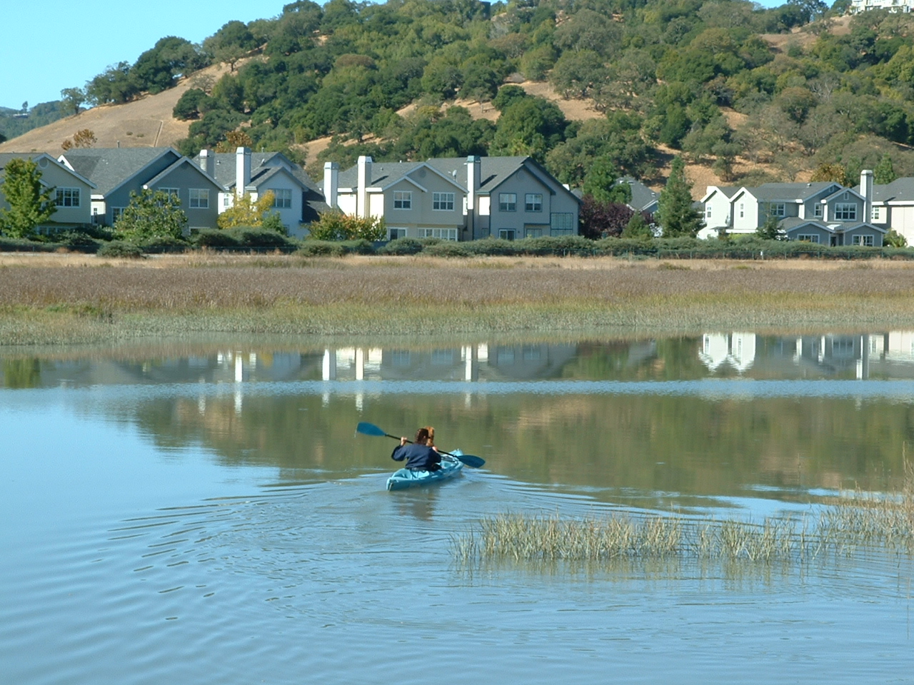 A kayaker paddles past waterfront homes on the marsh at the edge of Santa Venetia.
