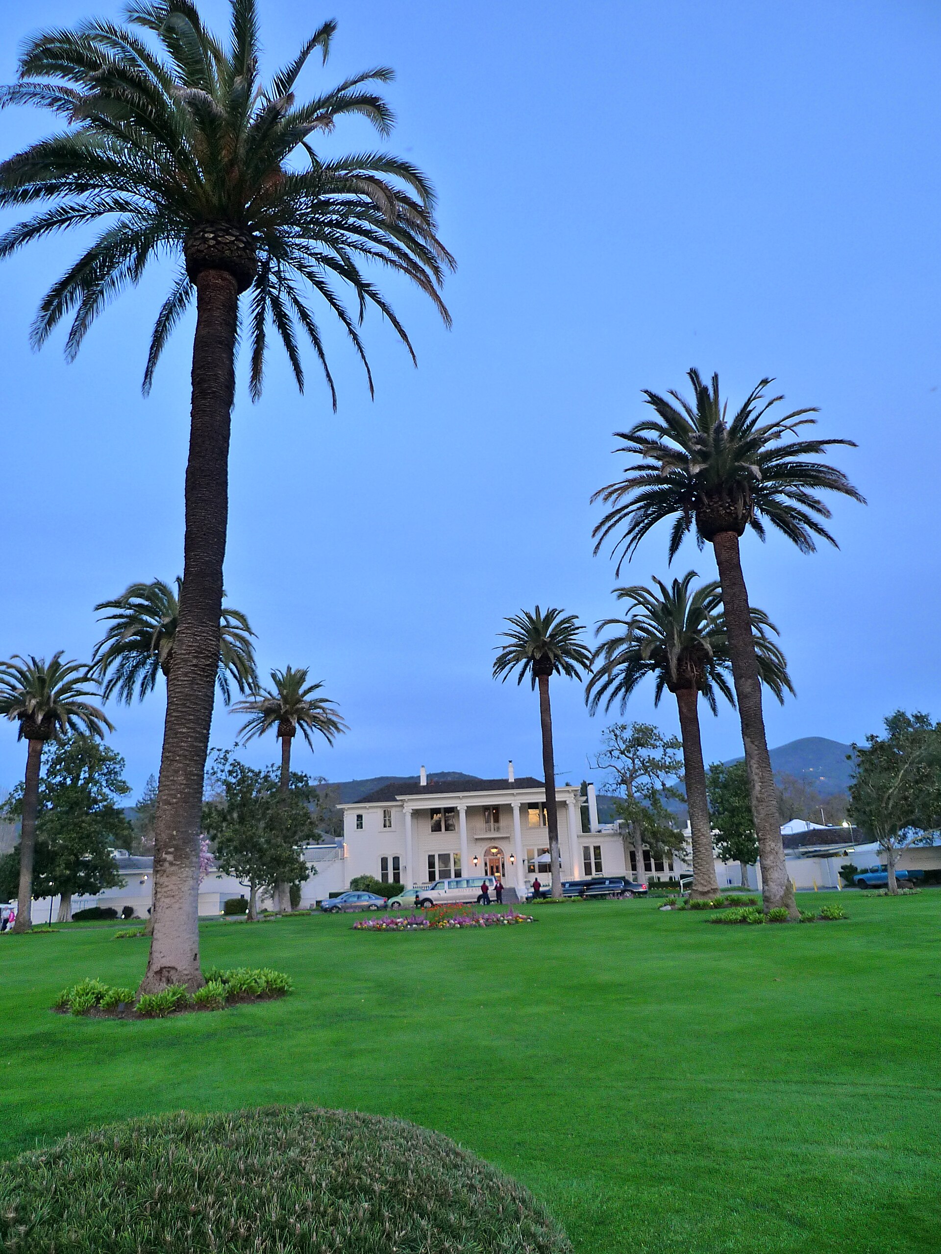The Silverado Resort's historic mansion with tall palm trees and manicured lawns at dusk.