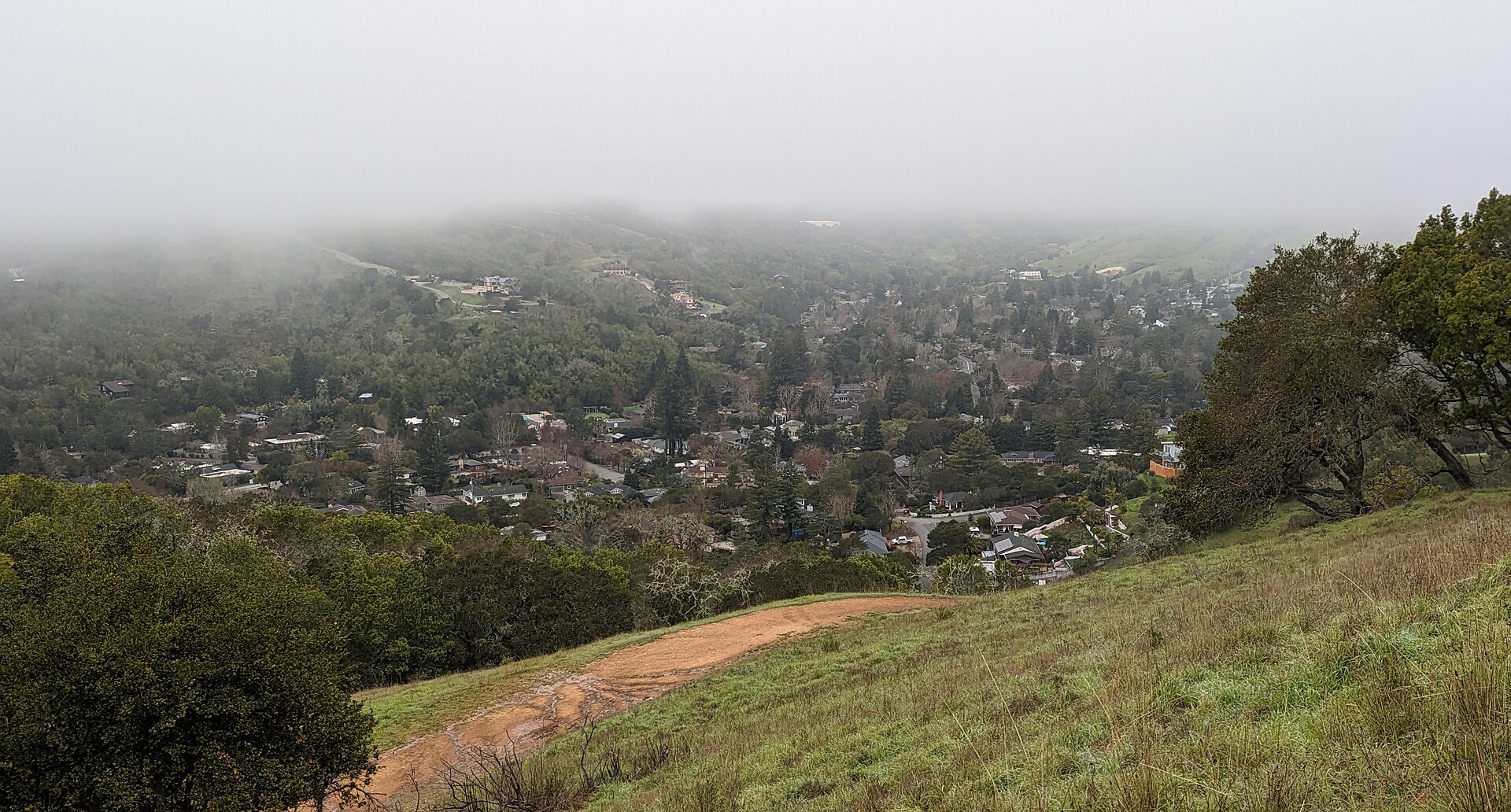 The Sleepy Hollow valley in morning fog, with houses scattered across the green hills.