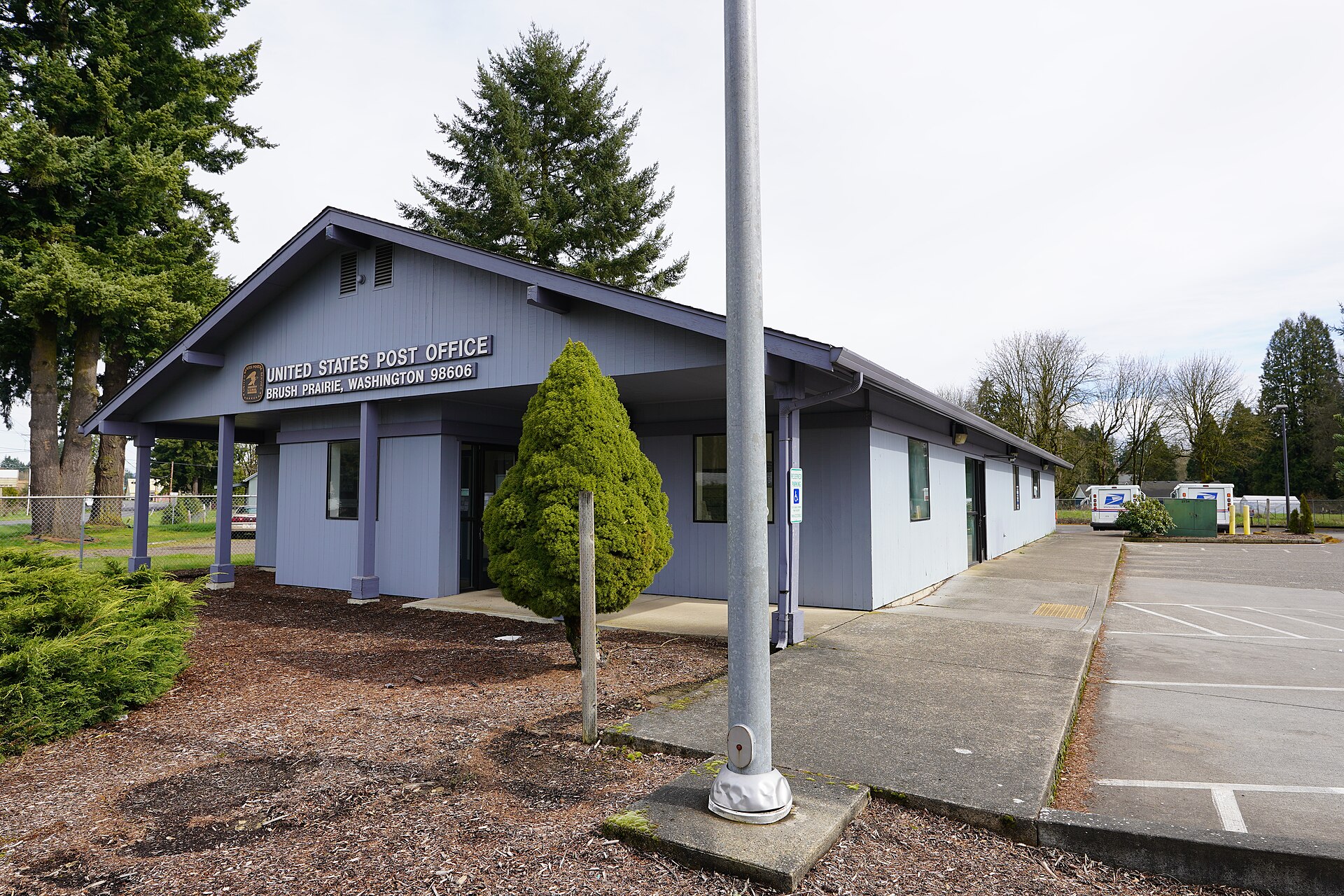 A blue post office building with a parking lot in Brush Prairie, Washington.