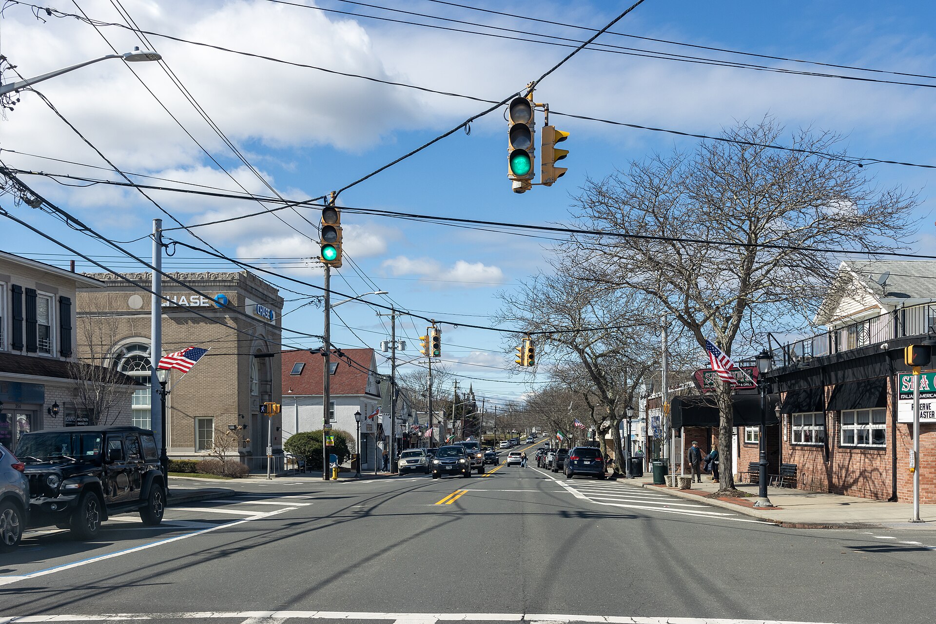 Montauk Highway approaching downtown Center Moriches, New York, with shops and traffic lights.